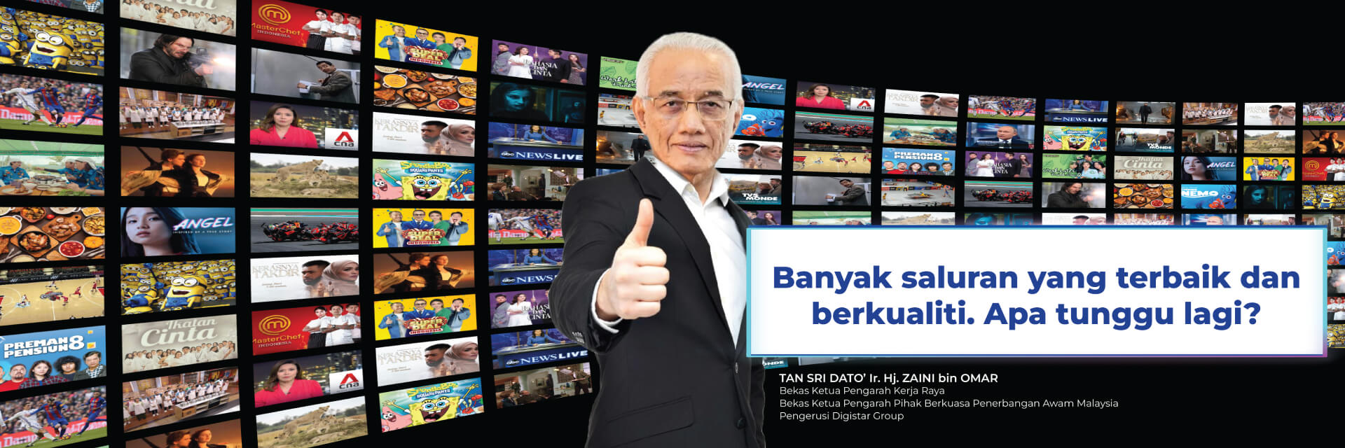 An old man wearing glasses, in a black suit and giving a thumbs up, stands in front of a collage of various TV screens
